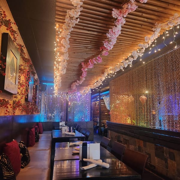 Saii Asian Bistro's dining room with cherry blossom garlands, string lights, and booth seating.