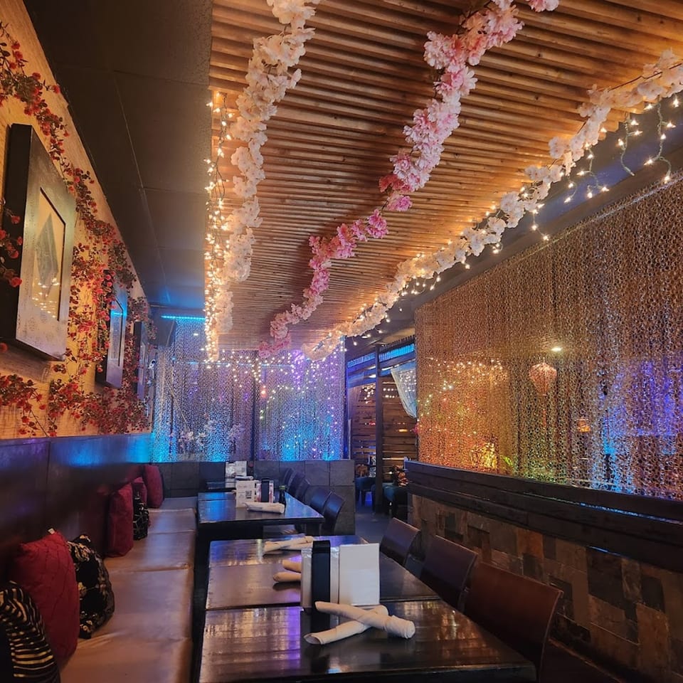 Saii Asian Bistro's dining room with cherry blossom garlands, string lights, and booth seating.