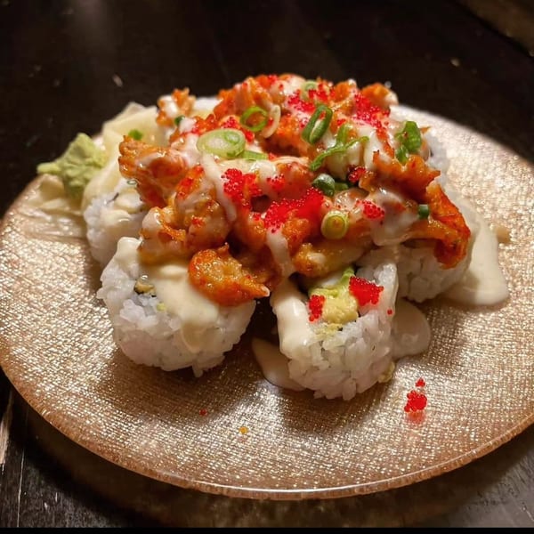 Saii Asian Bistro's sushi rolls topped with spicy sauce, red roe, and green onions on a gold plate.
