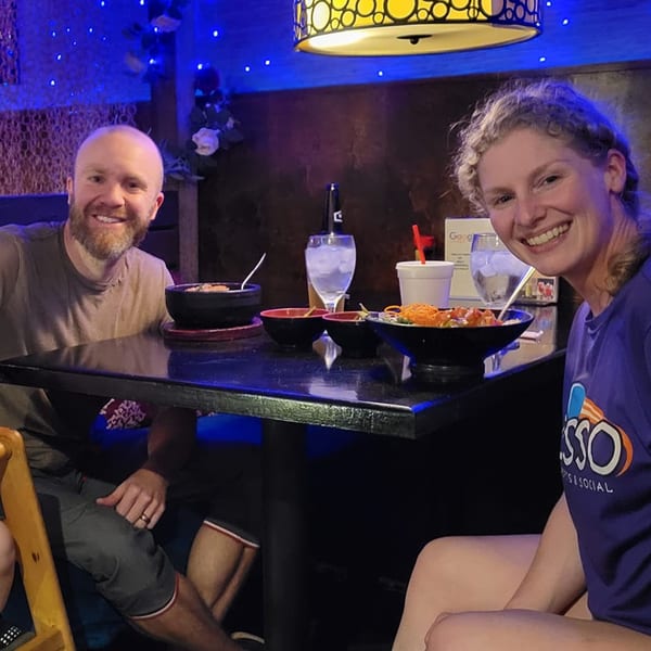 Smiling couple enjoying sushi and drinks at a table in Saii Asian Bistro.