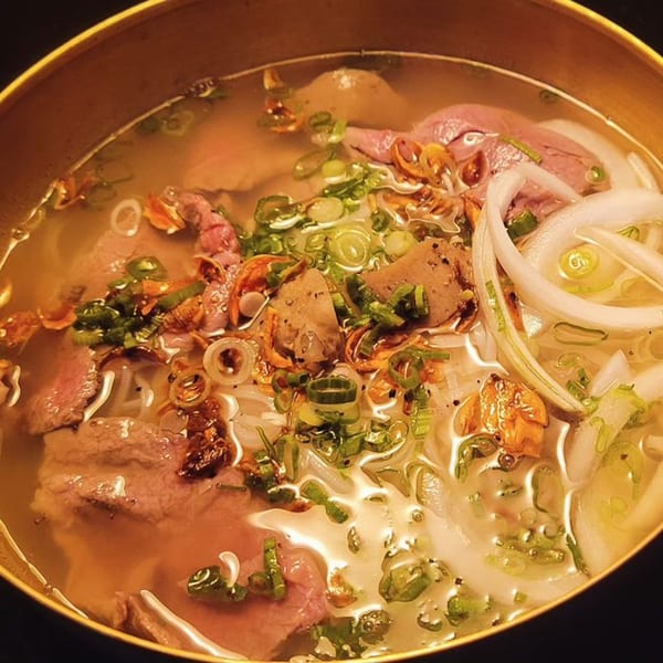 Close-up of a bowl of Saii Asian Bistro's pho with beef, noodles, onions, and scallions.